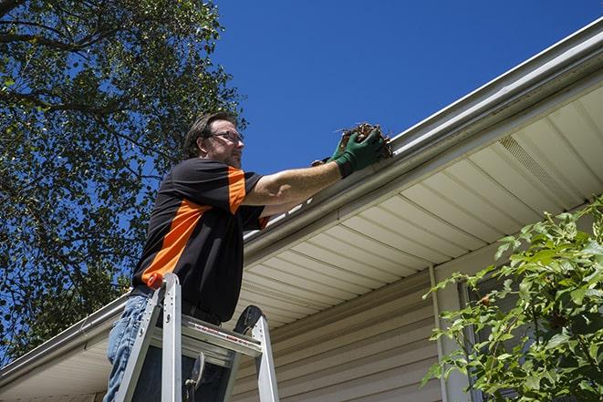 worker repairing damaged gutter on a residential roof in Cerritos